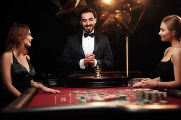 A professional dealer in a tuxedo greeting players at the roulette table, symbolizing the authentic live casino feel at BDKK.