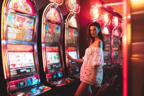 A stylish woman beside vibrant slot machines displaying glowing sevens, showcasing the variety of top slots at BDKK.